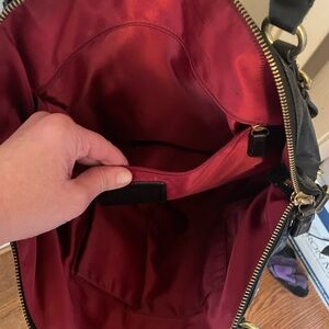 Genuine Coach bag in sleek black leather with shoulder strap and handles.